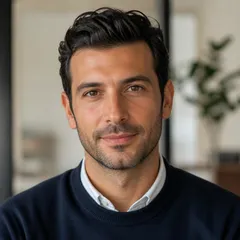 Professional author portrait with a natural smile, smart casual attire, and modern blurred office background.